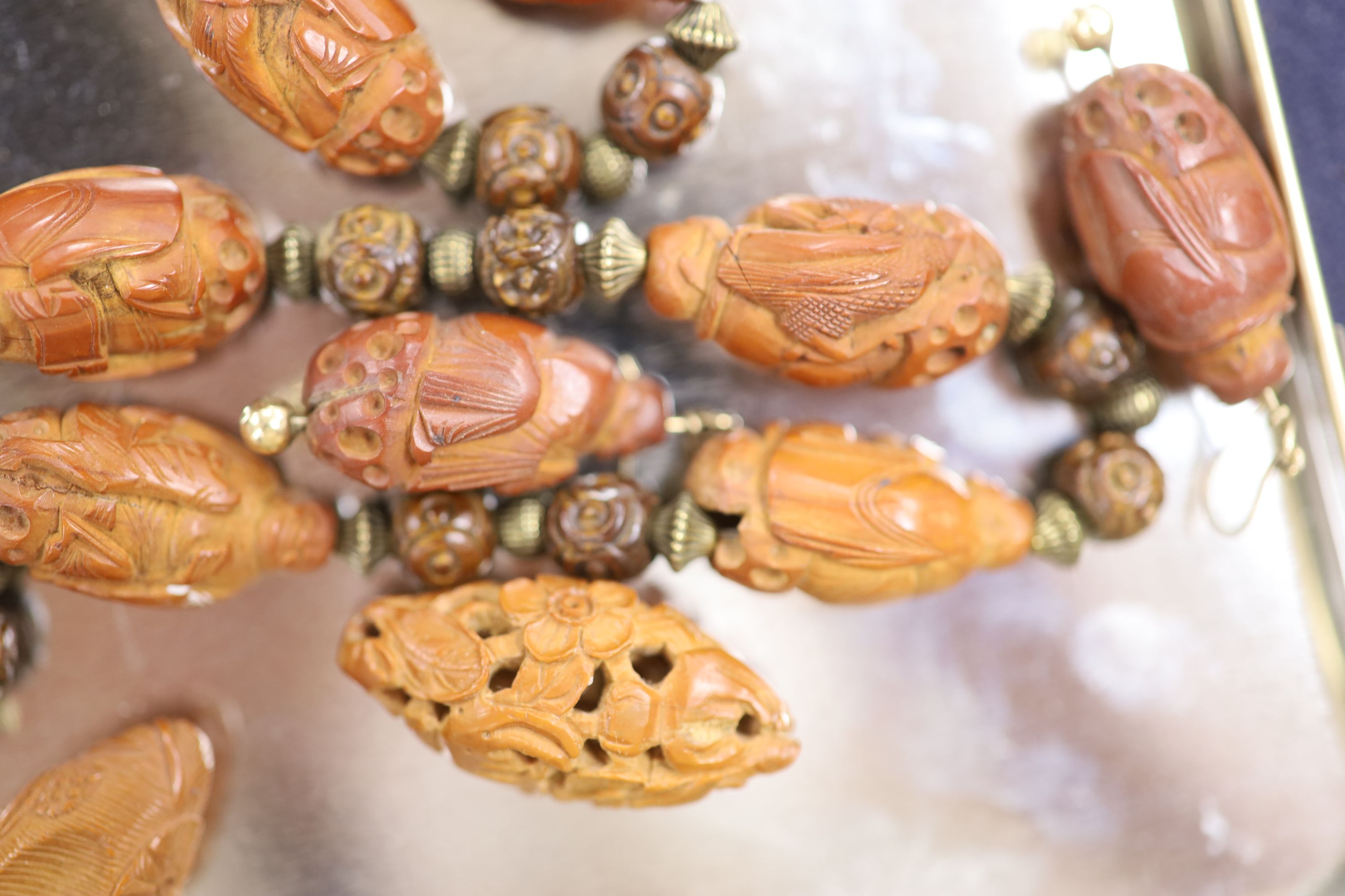 A Chinese peach stone or nut bead necklace, bracelet, a pair of earrings and two carved beads
